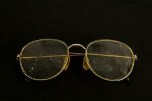 a pair of glasses with gold rims on a black background photo