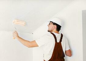 Color of year 2024, Peach Fuzz. man in overalls and hard hat painting wall photo