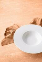 Color of the year 2024, Peach Fuzz. empty plate for serving pasta or soup, on blue background photo