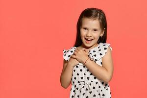 Close-up studio shot of beautiful brunette little girl posing against a pink background. photo