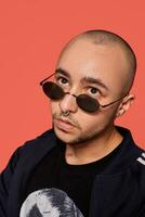 Studio shot of a young tattoed bald man posing against a pink background. 90s style. photo