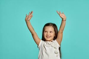 Close-up studio shot of beautiful brunette little girl posing against a blue background. photo