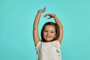 Close-up studio shot of beautiful brunette little girl posing against a blue background. photo