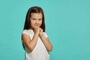 Close-up shot of a cute brunette little girl in a white blouse posing against a blue background. photo