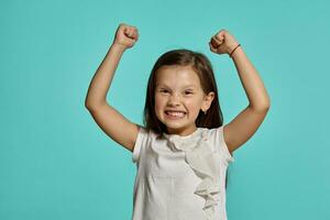 Close-up studio shot of beautiful brunette little girl posing against a blue background. photo