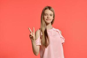 Studio portrait of a beautiful girl blonde teenager in a rosy t-shirt posing on pink background. photo