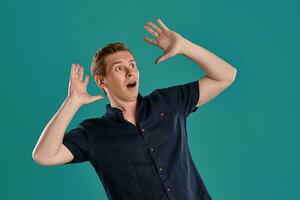 Close-up portrait of a ginger guy in navy t-shirt posing on blue background. Sincere emotions. photo