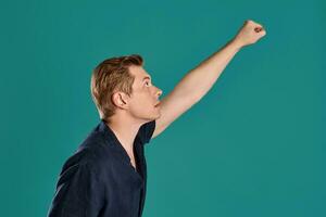 Close-up portrait of a ginger guy in navy t-shirt posing on blue background. Sincere emotions. photo