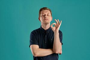 Close-up portrait of a ginger guy in navy t-shirt posing on blue background. Sincere emotions. photo