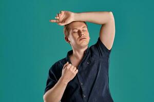 Close-up portrait of a ginger guy in navy t-shirt posing on blue background. Sincere emotions. photo