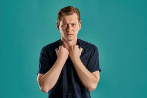 Close-up portrait of a ginger guy in navy t-shirt posing on blue background. Sincere emotions. photo