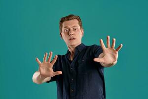 Close-up portrait of a ginger guy in navy t-shirt posing on blue background. Sincere emotions. photo