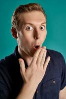 Close-up portrait of a ginger guy in navy t-shirt posing on blue background. Sincere emotions. photo