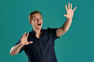 Close-up portrait of a ginger guy in navy t-shirt posing on blue background. Sincere emotions. photo