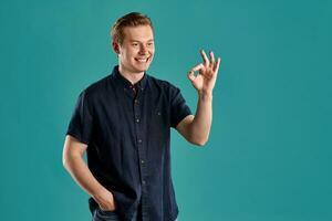 Close-up portrait of a ginger guy in navy t-shirt posing on blue background. Sincere emotions. photo