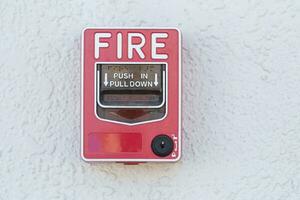 Red fire alarm switch at cement wall photo