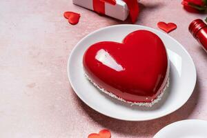 heart shaped glazed valentine cake, gift and wine on pink concrete background photo