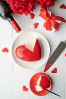 heart shaped glazed valentine cake and flowers on wooden table photo