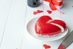 heart shaped glazed valentine cake and flowers on wooden table photo