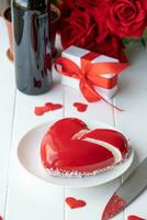 heart shaped glazed valentine cake and flowers on wooden table photo
