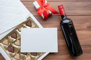 valentine sweet chocolate and red wine on wooden background photo