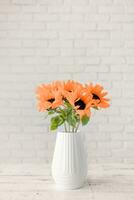 Color of the year 2024, Peach Fuzz. A bouquet of sunflowers in a vase against the background of a white brick wall. Copy space for text. photo