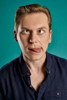 Close-up portrait of a ginger guy in navy t-shirt posing on blue background. Sincere emotions. photo