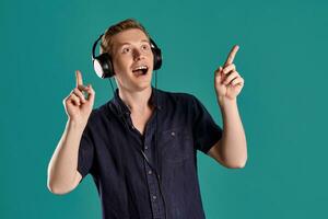 Close-up portrait of a ginger guy in navy t-shirt posing on blue background. Sincere emotions. photo