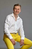 Close-up portrait of a ginger guy in white shirt posing on gray background. Sincere emotions. photo