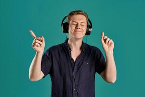 Close-up portrait of a ginger guy in navy t-shirt posing on blue background. Sincere emotions. photo