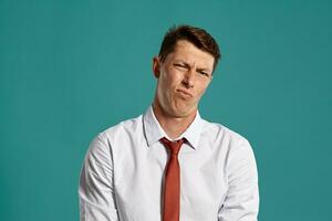 Young man in a classic white shirt and red tie posing over a blue background. photo