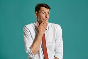 Young man in a classic white shirt and red tie posing over a blue background. photo