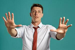 Young man in a classic white shirt and red tie posing over a blue background. photo