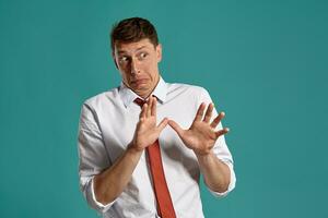 Young man in a classic white shirt and red tie posing over a blue background. photo