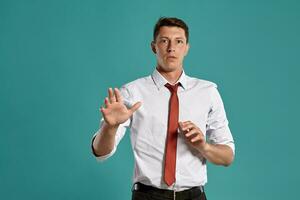 joven hombre en un clásico blanco camisa y rojo Corbata posando terminado un azul antecedentes. foto