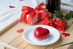 heart shaped glazed valentine cake and flowers on wooden tray photo