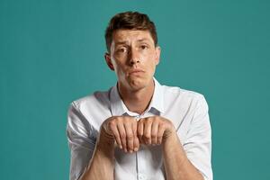 Portrait of a young brunet man posing in a studio against a blue background. photo