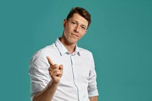 Young man in a classic white shirt is posing over a blue background. photo