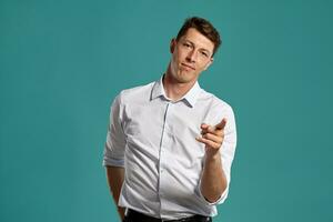 Young man in a classic white shirt is posing over a blue background. photo