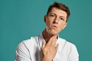 Portrait of a young brunet man posing in a studio against a blue background. photo