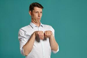 Young man in a classic white shirt is posing over a blue background. photo