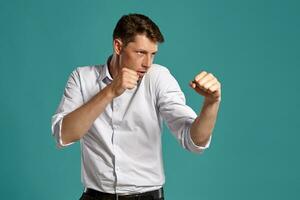 Young man in a classic white shirt is posing over a blue background. photo