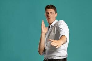 Young man in a classic white shirt is posing over a blue background. photo