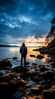 ai generado un hombre en pie en un rock mirando a el puesta de sol en el lago. foto