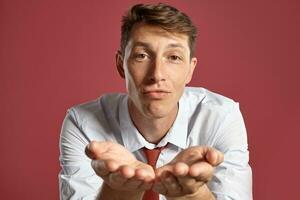 Portrait of a young brunet man posing in a studio against a red background. photo