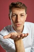 Portrait of a young brunet man posing in a studio against a red background. photo