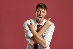 Young man in a classic white shirt and red tie posing over a pink background. photo