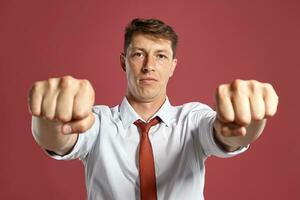 Portrait of a young brunet man posing in a studio against a red background. photo