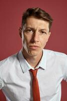 Portrait of a young brunet man posing in a studio against a red background. photo