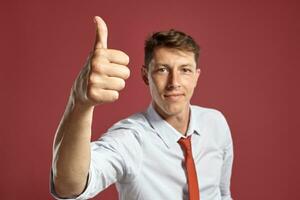 Portrait of a young brunet man posing in a studio against a red background. photo